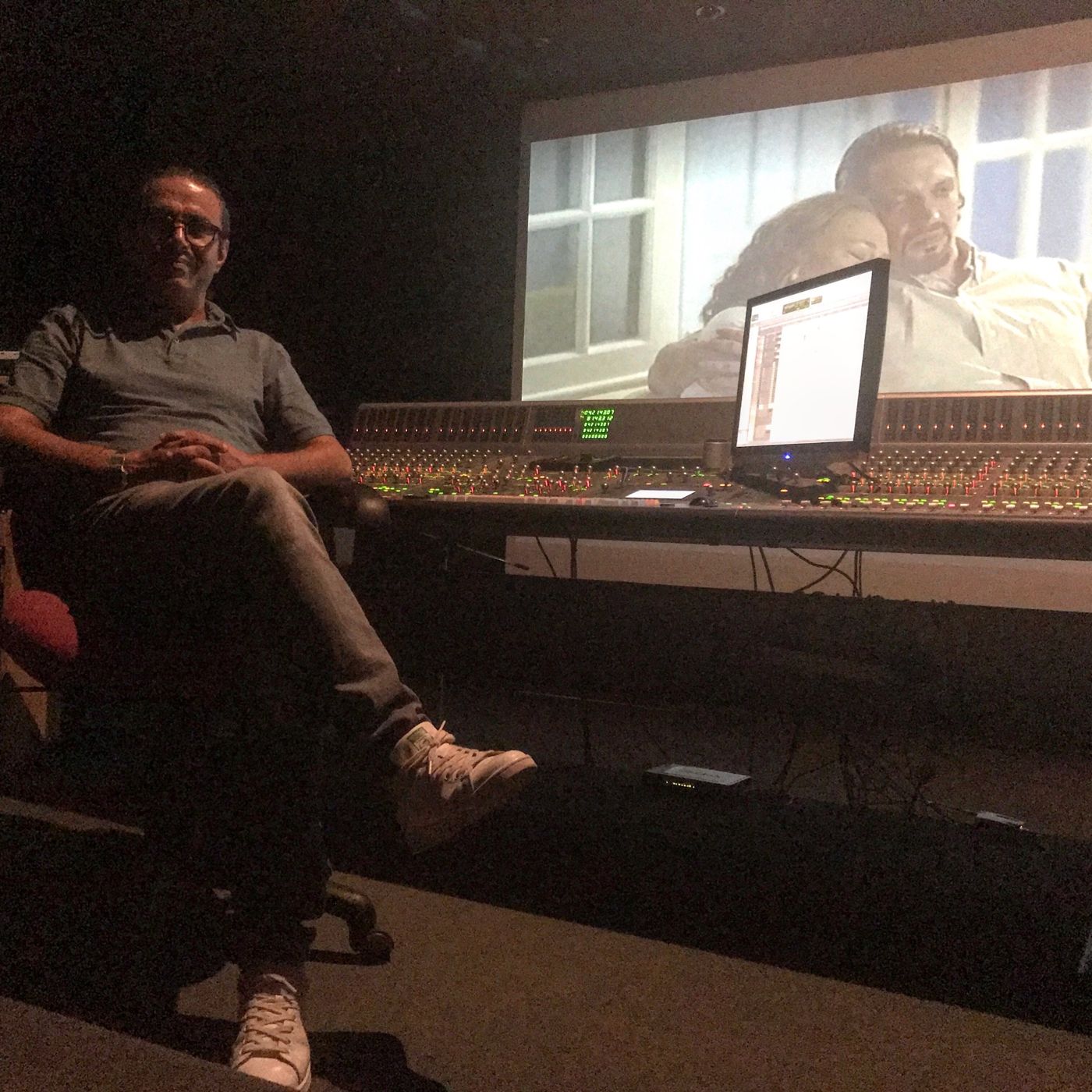 A man seated beside the mixing console, picture on the screen